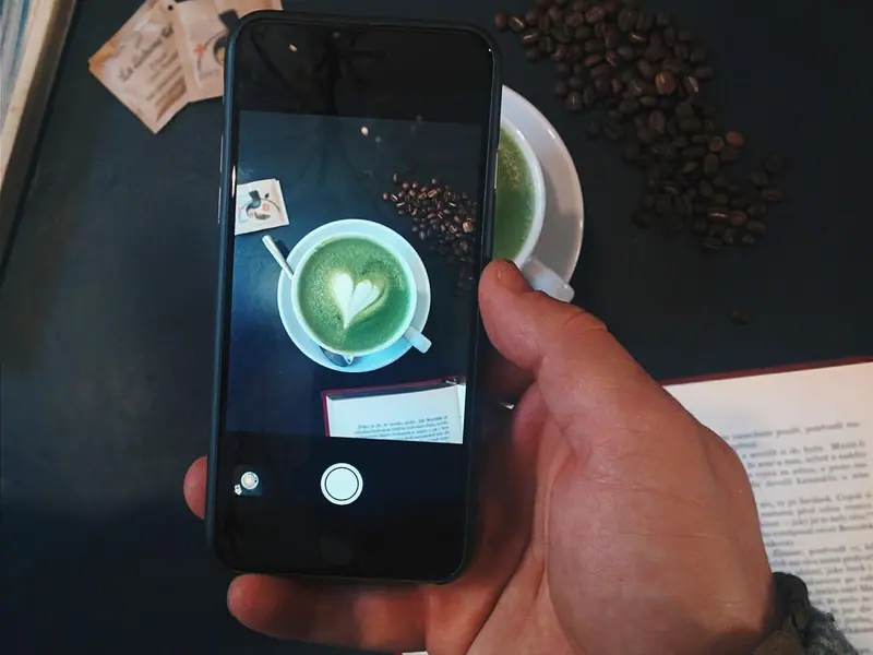 Phone photographing a latte for a café's social media