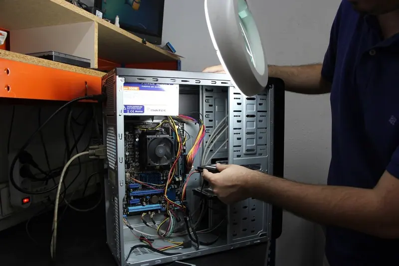 Technician's hands working inside an open desktop computer