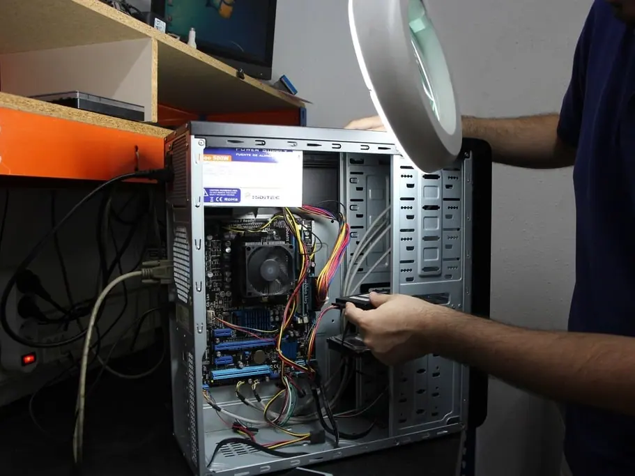Technician's hands working inside an open desktop computer